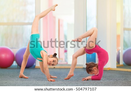 Flexible kids gymnasts doing acrobatic exercise in gym. Sport, training, fitness, yoga, active lifestyle concept
