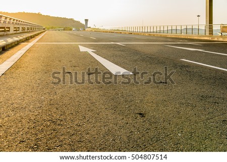 arrow forward on road at airport in sunset
