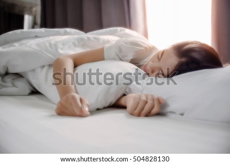 Cute girl on a soft white bed. She sleeping and relaxing. Royalty-Free Stock Photo #504828130
