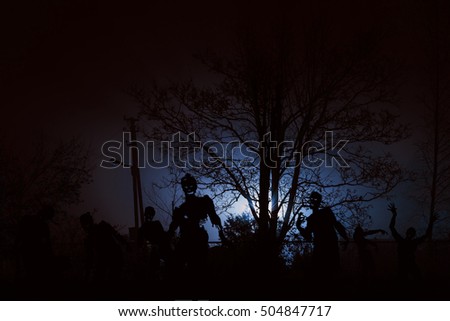 crowd of hungry zombies near residential buildings. Silhouettes of scary zombies walking at night