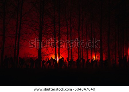 crowd of hungry zombies in the woods. Silhouettes of scary zombies walking in the forest at night. red alert Royalty-Free Stock Photo #504847840