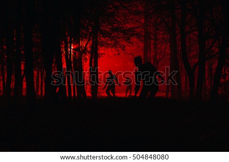 bloodthirsty zombies attacking. hungry zombies in the woods. Silhouettes of scary zombies walking in the forest at night Royalty-Free Stock Photo #504848080
