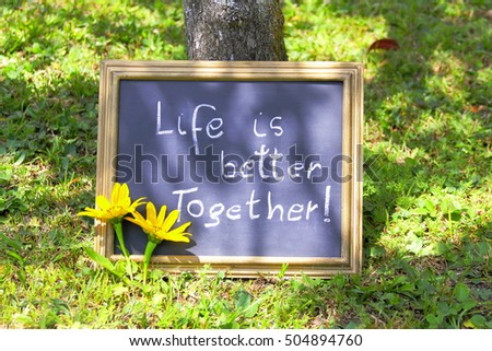 Motivation words: LIFE IS BETTER TOGETHER! Manuscript inspirational quotation on an outdoor banner with two Mexican sunflower and sunspot.    