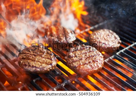 cooking burgers on hot grill with flames