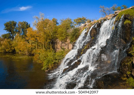 Waterfall with autumn colors trees  on a rock. Park at the monastic island