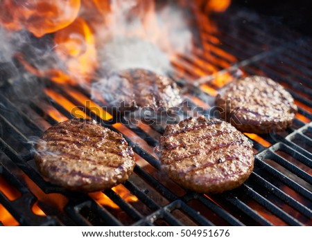 cooking burgers on hot grill with flames Royalty-Free Stock Photo #504951676