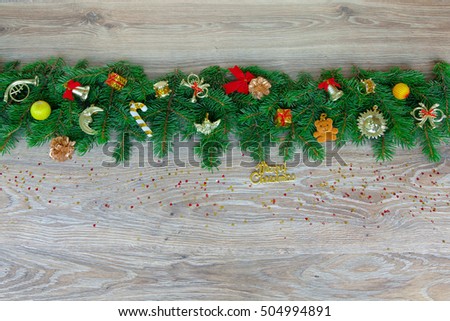 Christmas border - branches of pine with red and gold decorations and confetti, isolated on a natural wooden background, horizontal banner.