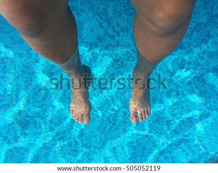 Two legs in blue water swimming pool
