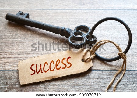 Keys to Success - Concept photo. Old key with paper label on wooden background - Success text.