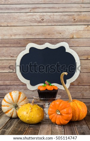 Pumpkin muffin with ornamental gourds and blank chalkboard sign
