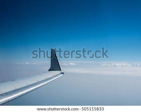 Wing of an airplane flying above the clouds. View of the sky from the window of the plane. The picture of the blue sky and airplane's wing. Foto of the airplain moving through the heaven.