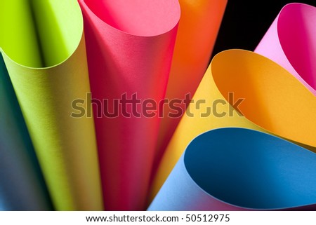 Colorful abstract and macro image of card stock in unique elliptical shapes with shadow effect and selective focus on a black background.