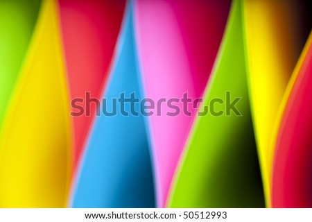Colorful abstract and macro image of card stock in unique elliptical shapes with shadow effect and selective focus on a black background.  Image taken with slight blur for additional effect.
