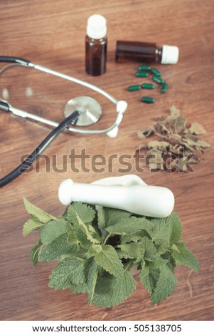 Vintage photo, Fresh green lemon balm in white mortar, stethoscope and medical capsules, choice between pills and alternative medicine, healthy lifestyle, herbalism