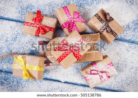 Wooden sled and wrapped gifts with colorful ribbons for Christmas, Valentine, birthday or other celebration lying on snowy boards