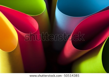 Colorful card stock in unique elliptical shapes with shadow effect and selective focus on a black background.