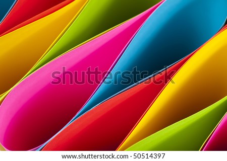 Colorful card stock in unique elliptical shapes with shadow effect and selective focus on a black background.