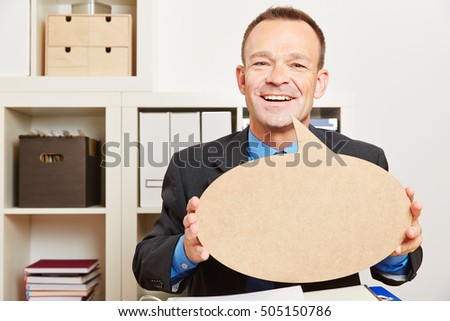 Happy business man in his office with an empty speech bubble