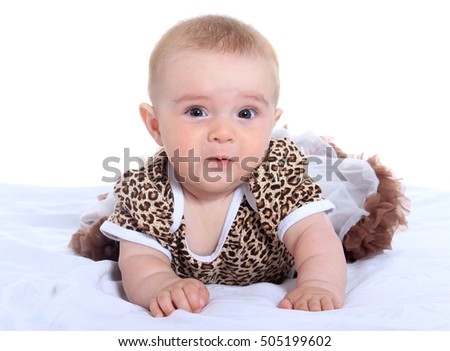 Adorable baby girl in a leopard dress on a blanket on a white background