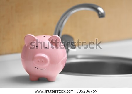Pig money box beside kitchen sink and tap