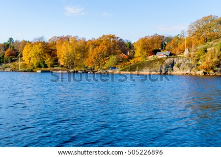 Coastal landscape in fall with cliffs and colorful trees. Houses visible in the terrain. Jarnavik archipelago in southern Sweden. Royalty-Free Stock Photo #505226896