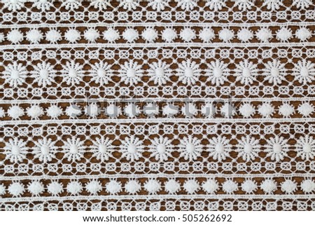 White lace floral pattern textile on wooden background