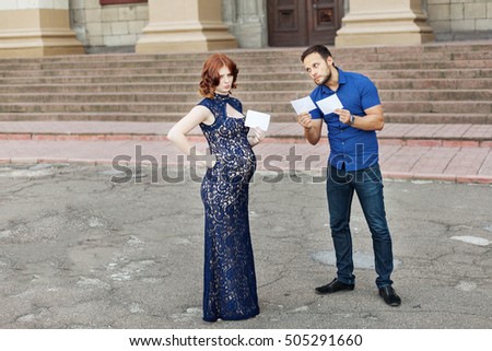 Funny image. Couple expecting a baby: they holds a signs with space for text "boy" or "girl". Pregnancy in long dress. Future daddy in jeans and blue shirt.