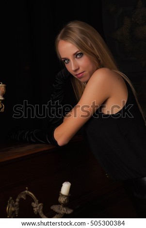 beautiful blonde at the piano in the gloom, dressed in a black outfit