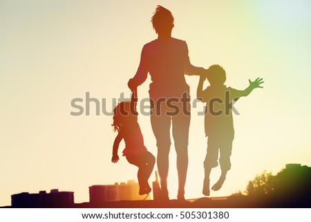 happy family - father with kids jumping from joy at sunset