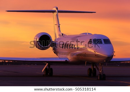 Modern business jet standing on a parking position during sunrise. Royalty-Free Stock Photo #505318114