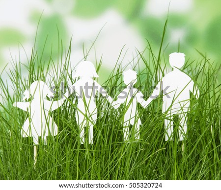 Family cut out of paper figures of in the grass on abstract green background. Ecology concept.