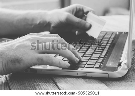 Man Hands holding credit card and using laptop. Online shopping, online banking and online marketing. shallow depth of field, black and white toning photo