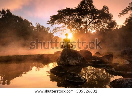 Young woman meditating by the lake Royalty-Free Stock Photo #505326802
