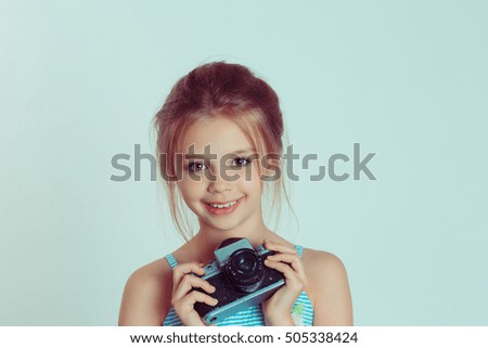 Cute little girl holding taking pictures with vintage camera looking at you camera isolated green wall background