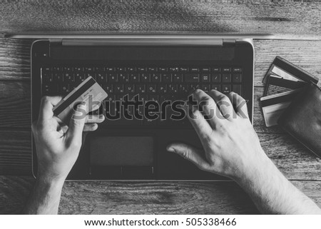 Man Hands holding credit card and using laptop. Online shopping and online marketing. cyber Monday, black Friday,  black and white toning photo
