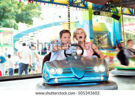 Senior couple in the bumper car at the fun fair Royalty-Free Stock Photo #505343602