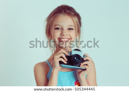 Beautiful smiling happy child (kid, girl) holding taking pictures looking at you camera gesture