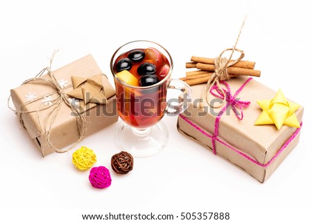 Glass of delicious glintwein or mulled hot wine, cinnamon, clews of yellow, brown, pink thread and gifts wrapped in craft paper with bow and snowflakes isolated on white background