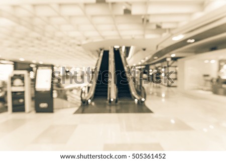 Blur image of information kiosk next and escalator at modern shopping mall in Southeast Asia. Abstract background shopping mall store interior. Business concept.