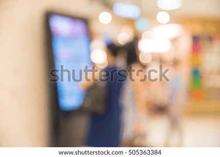 Blur image of people looking at the information kiosk in modern shopping mall in Southeast Asia. Motion blur of shoppers at shopping center. Abstract blur background of shopping mall store interior.