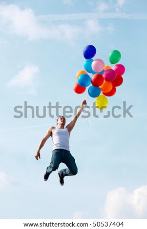 Image of young man jumping and holding colorful balloons