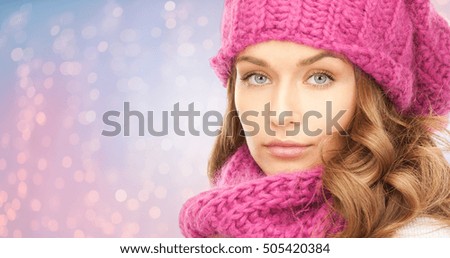 winter holidays, christmas and people concept - close up of young woman in hat and scarf over rose quartz and serenity lights background