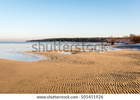 frozen beach view by the baltic sea with sand and ice in water