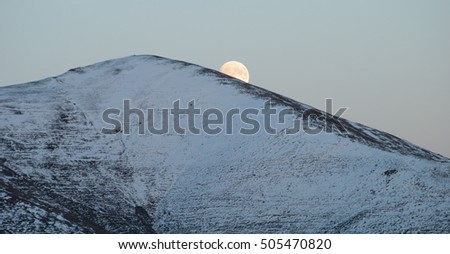 A beautiful moonrise in the mountains. Snowy mountain peak in the Carpathians, Ukraine, Europe.