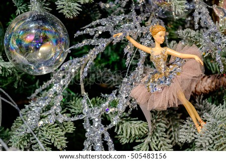 Ballerina toy decoration on a Christmas tree branch with a glass ball.