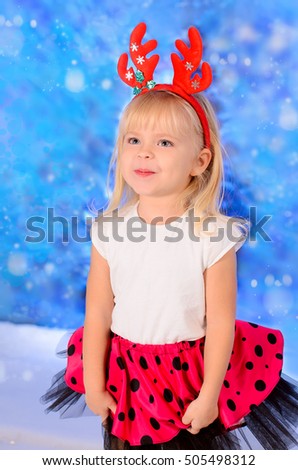 Pretty blond girl with Christmas reindeer horns on his head, in red skirt with polka dots