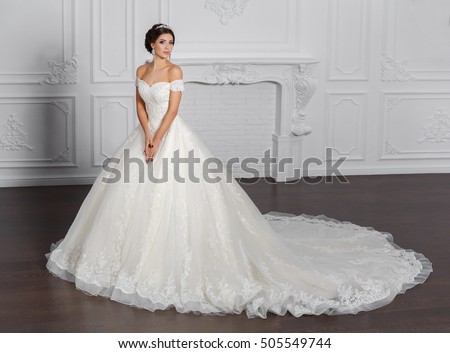 Fashion bride in gorgeous wedding dress studio portrait. Beautiful model with bridal makeup and hairstyle in marriage lace dress.