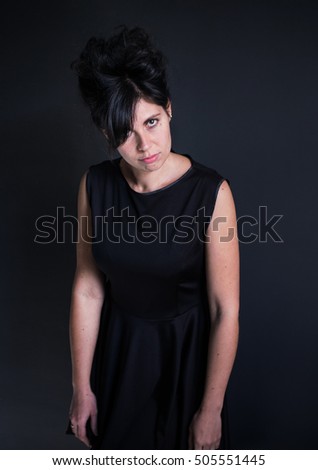 photo capricious woman in a black dress with a high hairdo hands down