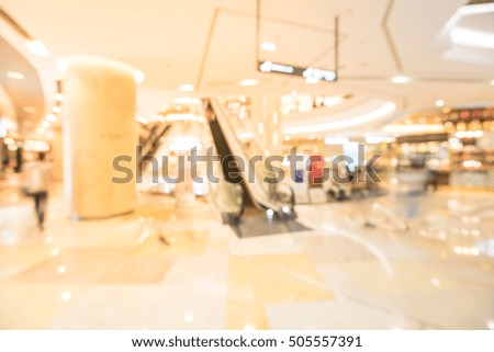 Blur image people in motion in escalators at modern shopping mall in Southeast Asia. Motion blur of shoppers at shopping center. Abstract background shopping mall store interior with bokeh light.