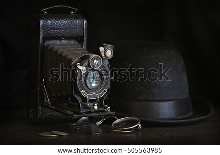 Old film camera with black bowler hat and glasses in the dark
